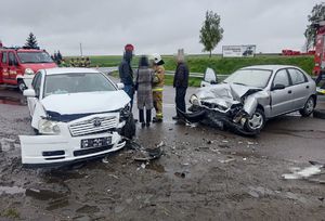 dwa rozbite pojazdy po wypadku, obok strażacy