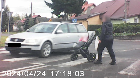zdjęcie z videorejestraotra. Mężczyzna przechodzi przez przejście z wózkiem, przed nim widać pojazd koloru srebrnego